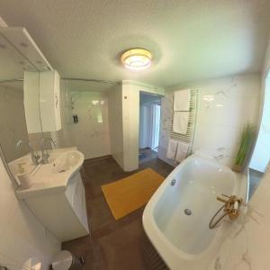 un bagno bianco con vasca e lavandino di Ferienhaus Strassgartl a Pinsdorf