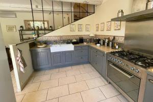 a large kitchen with blue cabinets and a stove at La Maison de Clervie in Mouriès