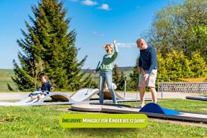 un hombre y una mujer y un niño jugando en un patio de recreo en AHORN Hotel Am Fichtelberg, en Kurort Oberwiesenthal