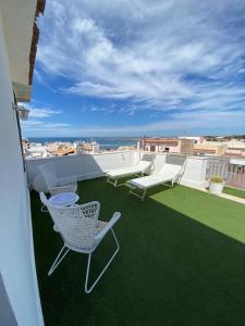 a balcony with chairs and tables on a roof at Attico con vista mozzafiato a due passi dal mare in Terrasini