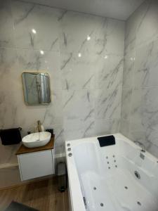 une salle de bain blanche avec une baignoire et un lavabo dans l'établissement L'Experience Appartement & SPA Privé CHAMBERY, à Chambéry 13 autres photos