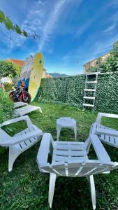 a group of white lounge chairs and a surfboard at Family House with pool & sea view in Bijela