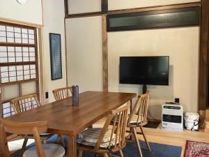 a dining room with a wooden table and chairs at 大自然に囲まれた築120年の隠れ家古民家で里山リラクゼーション in Isumi