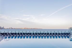 a pool with chairs and the ocean in the background at Melia Alicante in Alicante