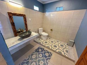Un baño con lavabo, inodoro y espejo. en Rumah Diyah Apartment, en Amed 26 fotos más