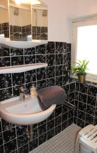 a bathroom with a sink and a black tiled wall at Landhaus Lippmann Whg6 in Grönwohldshorst