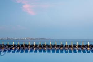 a row of chairs sitting on the edge of a swimming pool at Melia Alicante in Alicante