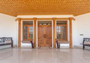 a room with two wooden doors and two benches at Lohono Stays Villa Noor in Srinagar