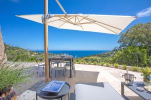a patio with a table and chairs and an umbrella at Villa La Louisière - Les Issambres in Saint-Peïre-sur-Mer