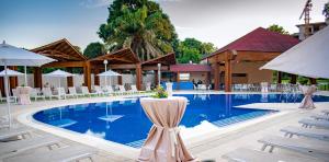a swimming pool with white chairs and a building at Grand Lancaster Brazzaville in Brazzaville