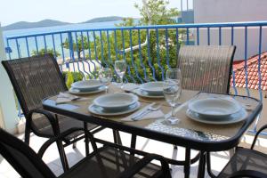 a table with plates and wine glasses on a balcony at AnaLev Apartment in Nea Peramos