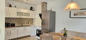 a kitchen with a table and a stainless steel refrigerator at Ferienwohnung Rodder Maar in Niederzissen