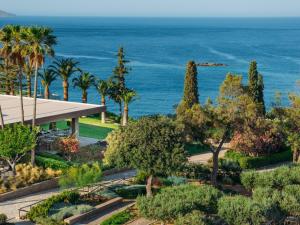 una vista de un jardín con el océano en el fondo en Minos Palace Hotel & Suites - Adults Only, en Agios Nikolaos