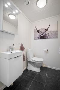 een badkamer met een toilet en een foto van een koe bij Voss Resort Bavallstunet in Skulestadmo