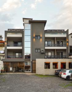 um prédio de apartamentos com carros estacionados em frente em CORYLUS Luxury Rooms & Suites em Leptokarya