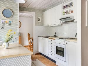 eine Küche mit weißen Schränken und einem Herd mit Backofen in der Unterkunft Chalet Kvarnfallet by Interhome in Ullared