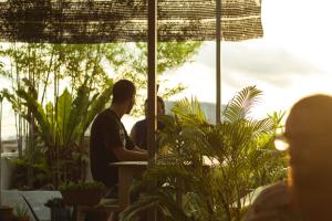 two men sitting at a table in a room with plants at Ringo's Foyer in Melaka