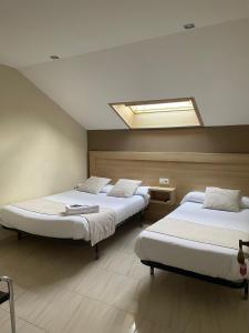 two beds in a room with a skylight at CASA MARUXA pensión in Pontevedra