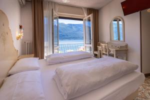 two beds in a bedroom with a view of the water at Hotel Villa Margherita in Limone sul Garda