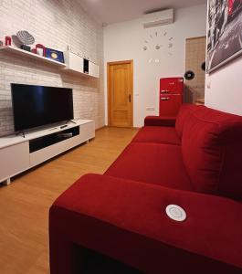 Una sala de estar con un sofá rojo y un televisor de pantalla plana. en Conil Alojamientos Manrey, en Conil de la Frontera