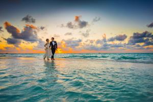 阿喬普羅柯皮歐斯的住宿－Virtu Suites，日落时分,一对夫妇站在海滩上