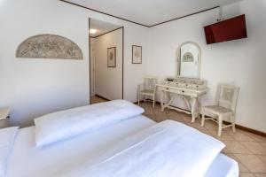 a bedroom with two beds and a table and a mirror at Hotel Villa Margherita in Limone sul Garda