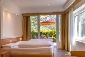 a bedroom with two beds and a large window at Hotel Villa Margherita in Limone sul Garda