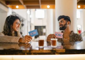 un hombre y una mujer sentados en una mesa sosteniendo señales en Ronil Goa - a JdV by Hyatt Hotel en Calangute