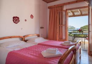 two beds in a room with a balcony at Ulisse Apartments in Paleokastritsa
