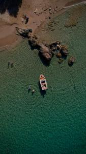 un barco en el agua junto a una playa en Virtu Suites, en Agios Prokopios