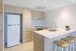 cocina con encimera, nevera y taburetes en beach residence 2-BR river view, en Gold Coast