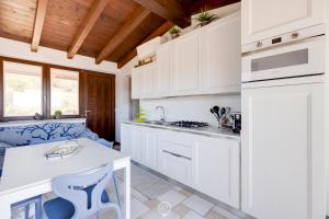 Una cocina con gabinetes blancos y encimera. en House Stella Charm, en Domus de Maria 28 fotos más