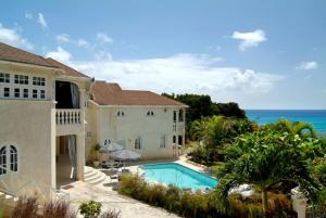 a house with a swimming pool next to the ocean at Sea Symphony Villa in Saint Lucy
