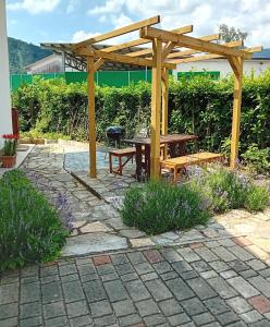 a wooden pergola with a picnic table and a bench at Apartma Gorjan in Tolmin
