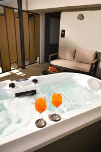 Dois copos de cocktails de laranja sentados numa banheira. em CORYLUS Luxury Rooms & Suites em Leptokarya