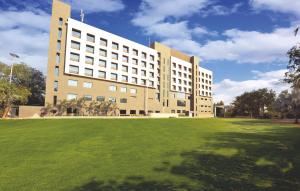 a large building with a grass field in front of it at Narayani Heights, Ahmedabad in Ahmedabad