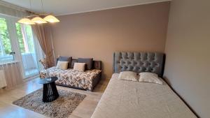 a bedroom with a bed and a couch and a table at Apartamentai su balkonu in Klaipėda