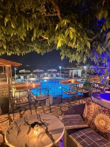 a patio with tables and chairs and a pool at night at Semiramis in Lefkada Town