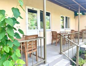 a patio with wooden chairs and tables and windows at Ассоль Коблеве in Koblevo