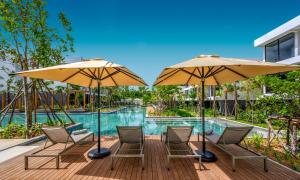 - un groupe de chaises longues et de parasols à côté de la piscine dans l'établissement Stay Wellbeing & Lifestyle Resort, à Rawai Beach