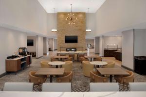 eine Lobby mit Tischen und Stühlen und einem TV in der Unterkunft Homewood Suites by Hilton Lackland AFB/SeaWorld, TX in San Antonio