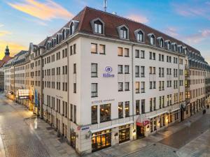 a large white building with a brown roof at Hilton Dresden an der Frauenkirche in Dresden