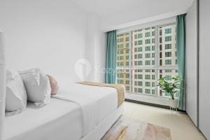 ein weißes Sofa in einem Zimmer mit Fenster in der Unterkunft Vesta by Kozystay - Gandaria in Jakarta