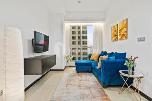 ein Wohnzimmer mit einem blauen Sofa und einem Fernseher in der Unterkunft Vesta by Kozystay - Gandaria in Jakarta