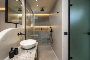 Celestial Lindos Suites في ليندوس: حمام مع حوض أبيض ومرآة