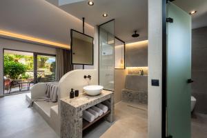 Celestial Lindos Suites في ليندوس: حمام مع حوض وغرفة استحمام