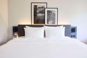 a bedroom with a white bed with three pictures on the wall at Radisson Blu Park Hotel, Oslo in Fornebu +94 photos