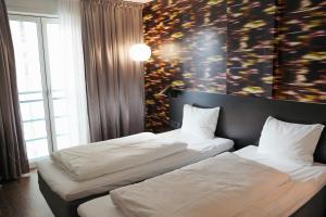 two beds in a room with a large window at Comfort Hotel Union Brygge in Drammen +30 photos