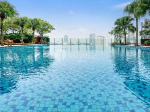 einen Pool mit blauem Wasser und Palmen in der Unterkunft Vesta by Kozystay - Gandaria in Jakarta