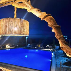 una lámpara de araña cuelga sobre una piscina por la noche en Semiramis en Lefkada